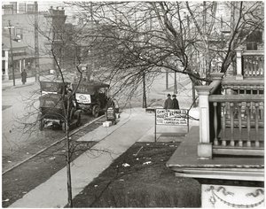Horizontal, black and white photograph showing an unidentified sidewalk scene